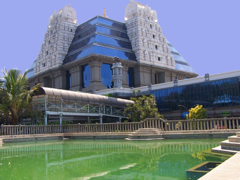 ISKCON Bangalore, temple, modern architecture, traditional design, reflective pool, clear sky, religious site, Hindu temple, landscaped grounds, peaceful ambiance