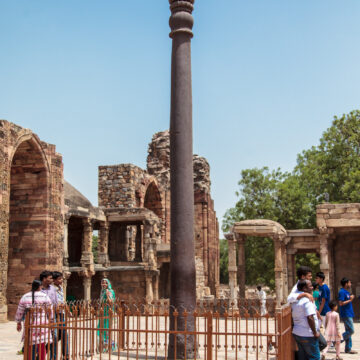 Iron Pillar of Delhi, Qutub Minar complex, ancient metallurgy, Indian history, historical monument, Delhi, India, ancient architecture, tourists, clear sky, heritage site, archaeological site, iron pillar, Ashokan pillar.