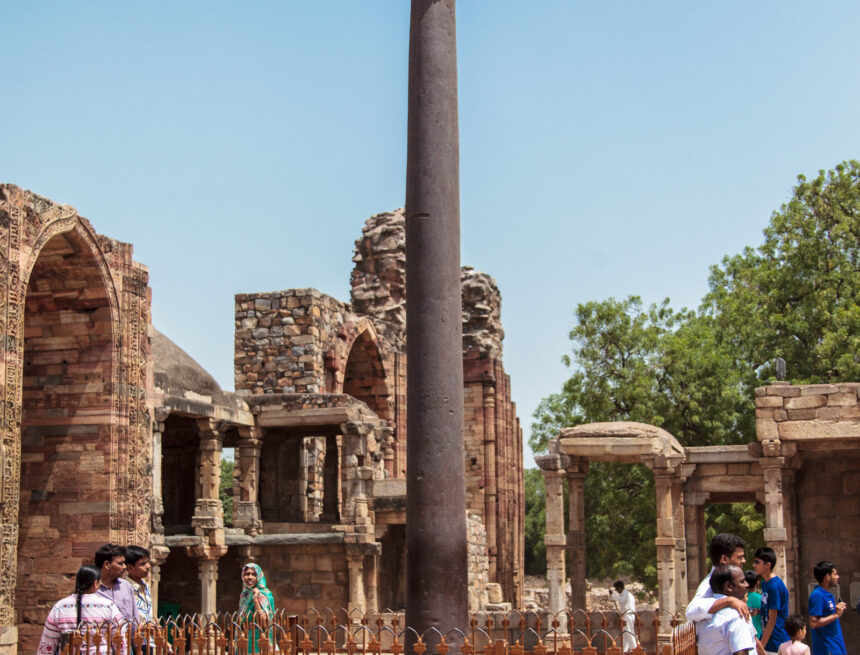 The iron pillar (also known as the Ashokan pillar) of Delhi Iron Pillar of Delhi, Qutub Minar complex, ancient metallurgy, Indian history, historical monument, Delhi, India, ancient architecture, tourists, clear sky, heritage site, archaeological site, iron pillar, Ashokan pillar.