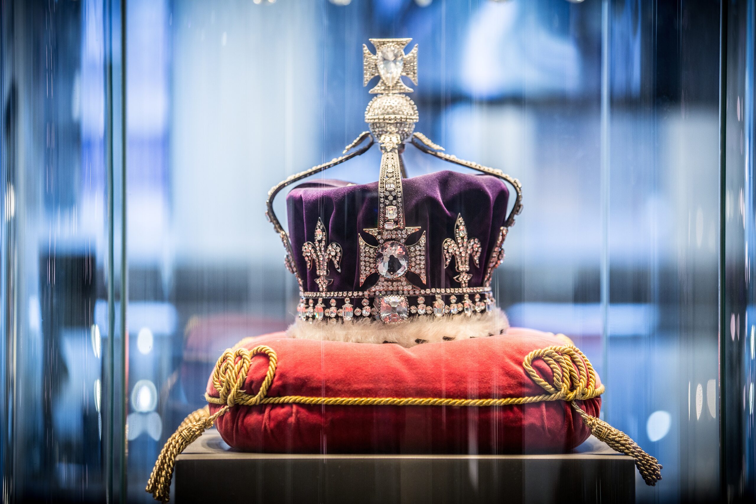 British crown, royal jewels, Kohinoor diamond, crown display, colonial heritage, gemstone crown, British monarchy, velvet cushion, royal exhibition, luxury artifact